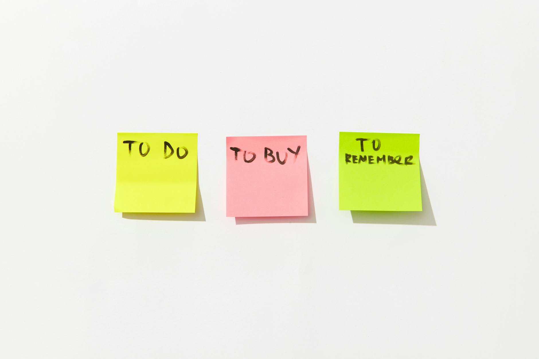 Trzy kolorowe karteczki z zadaniami na białym tle