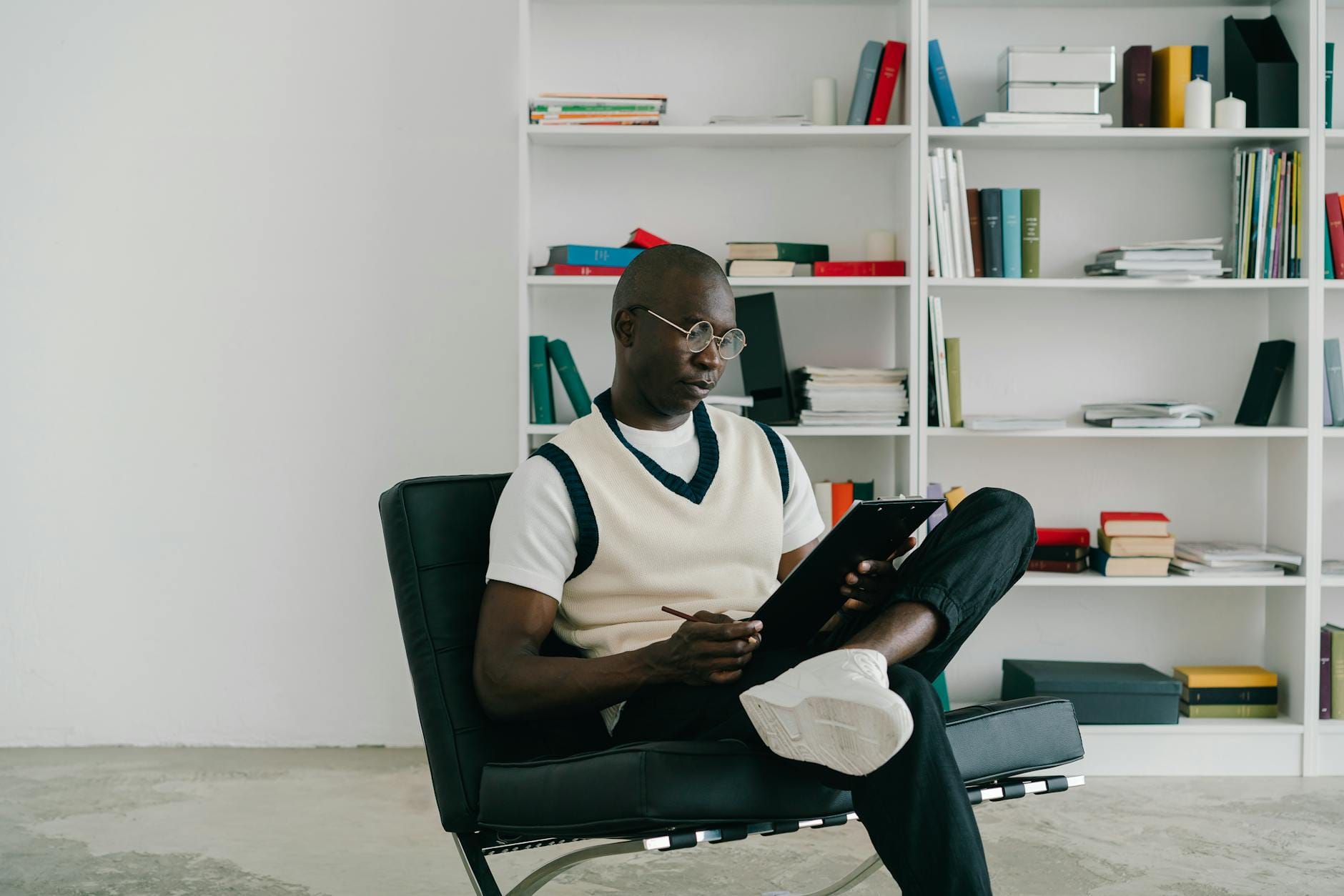 Mężczyzna w okularach czyta notatki na clipboardzie w nowoczesnym biurze