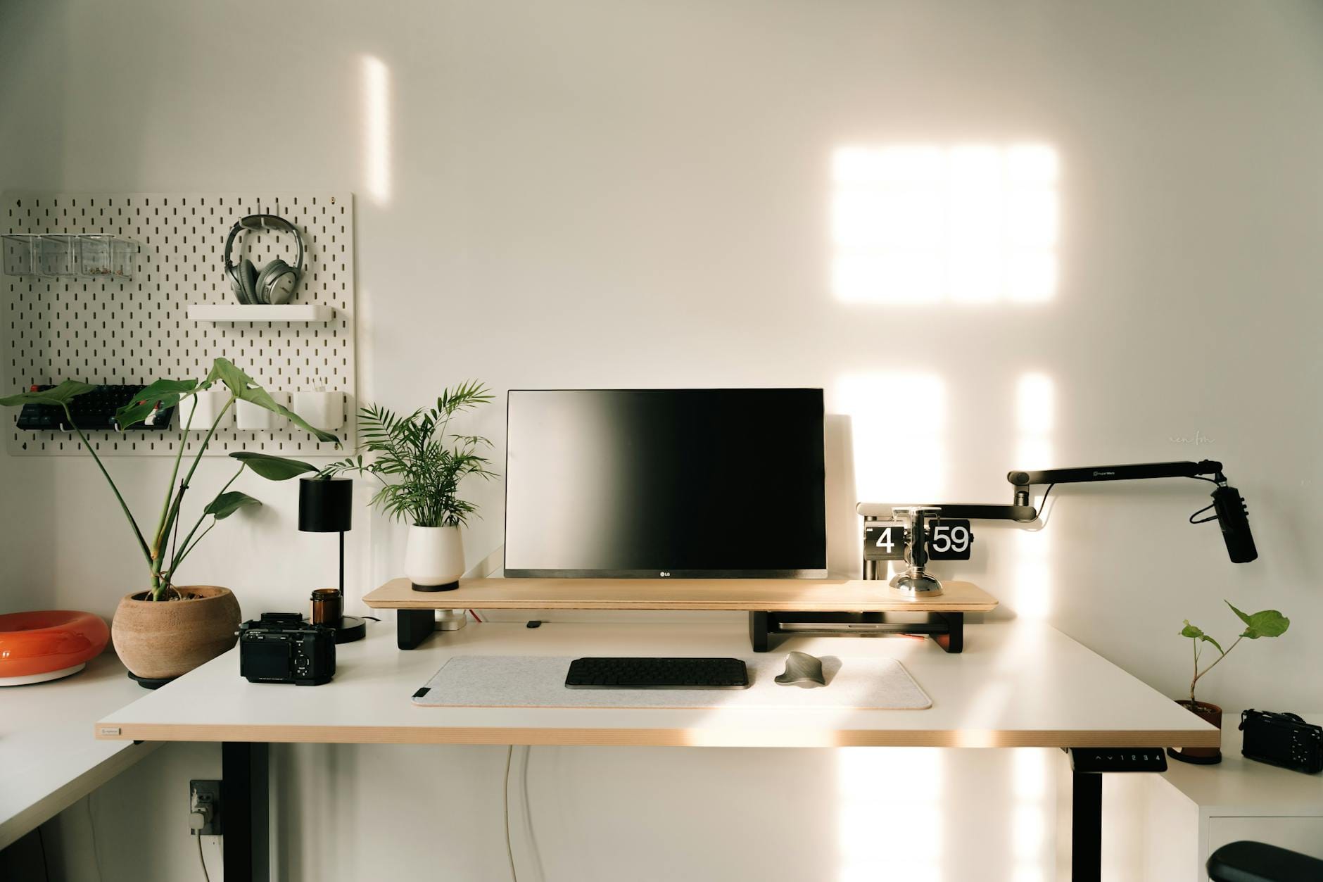 Minimalistyczne biurko domowe z monitorem, mikrofonem i roślinami