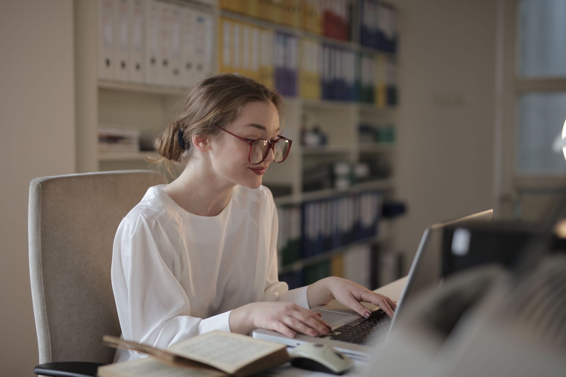 Kobieta w biurze pracuje przy laptopie, skupiona na ekranie