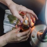 Dłonie trzymające butelkę kosmetyku w ciepłym, relaksującym świetle lampy
