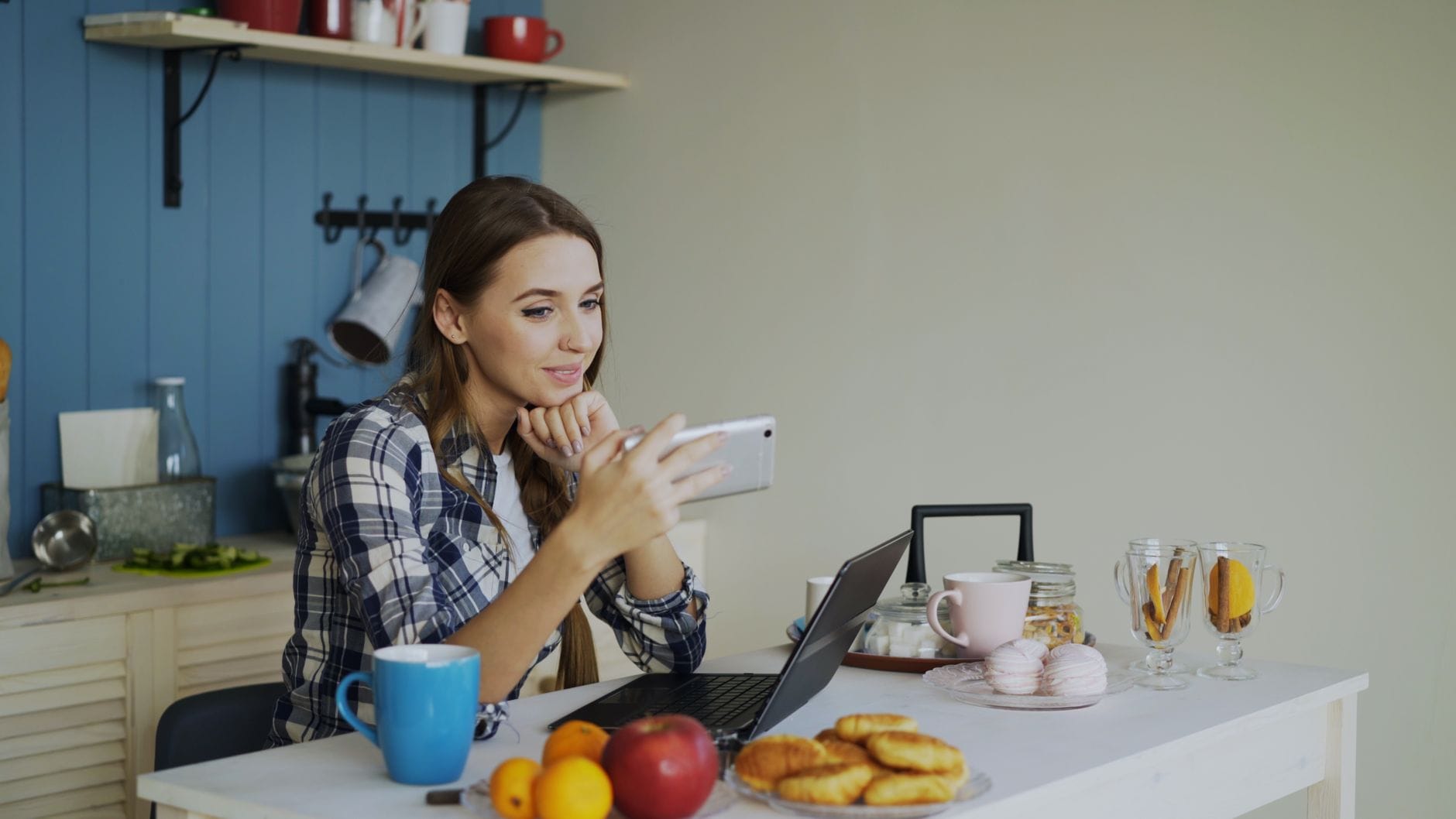 Kobieta przy śniadaniu pracuje zdalnie na laptopie w przytulnej kuchni