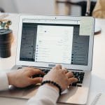 Osoba pisząca na laptopie w jasnym, nowoczesnym biurze